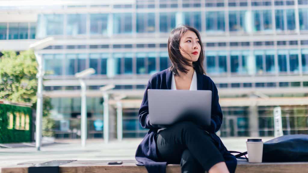 woman on computer outside office building
